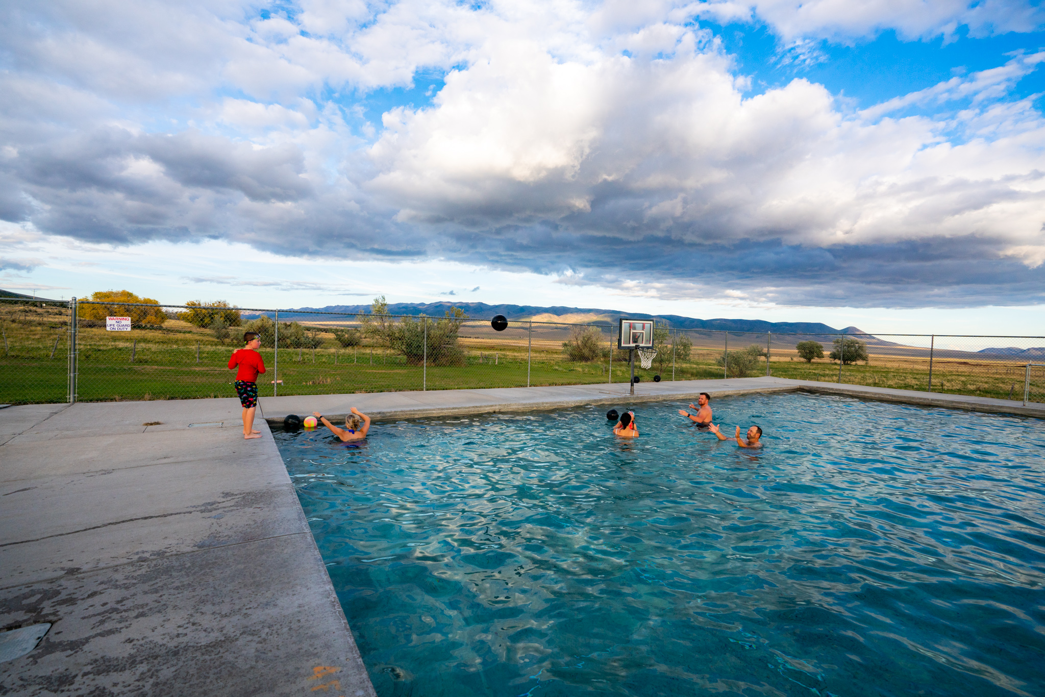 A six group of people play in a blue hot springs pool at Durfee Hot Springs.