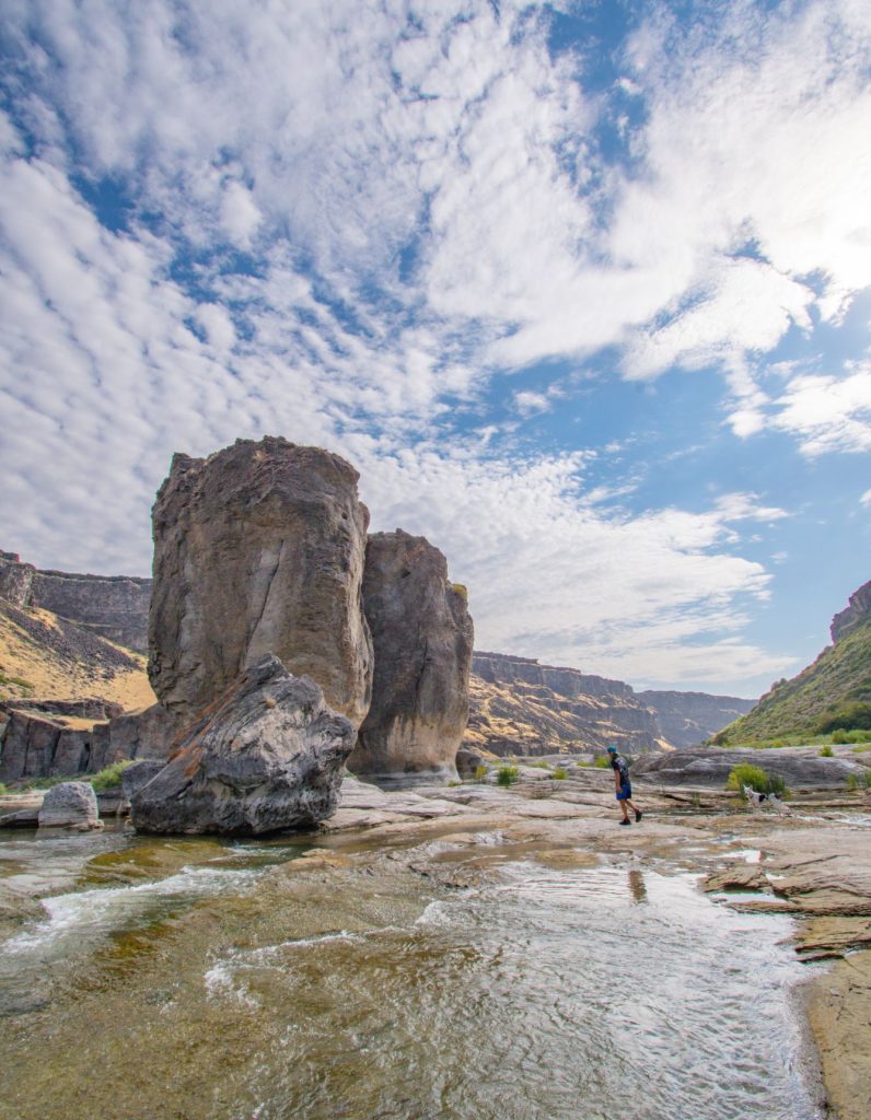 A hiker explores the rocky terrain surrounding the towering formations along the Pillar Falls Trail.