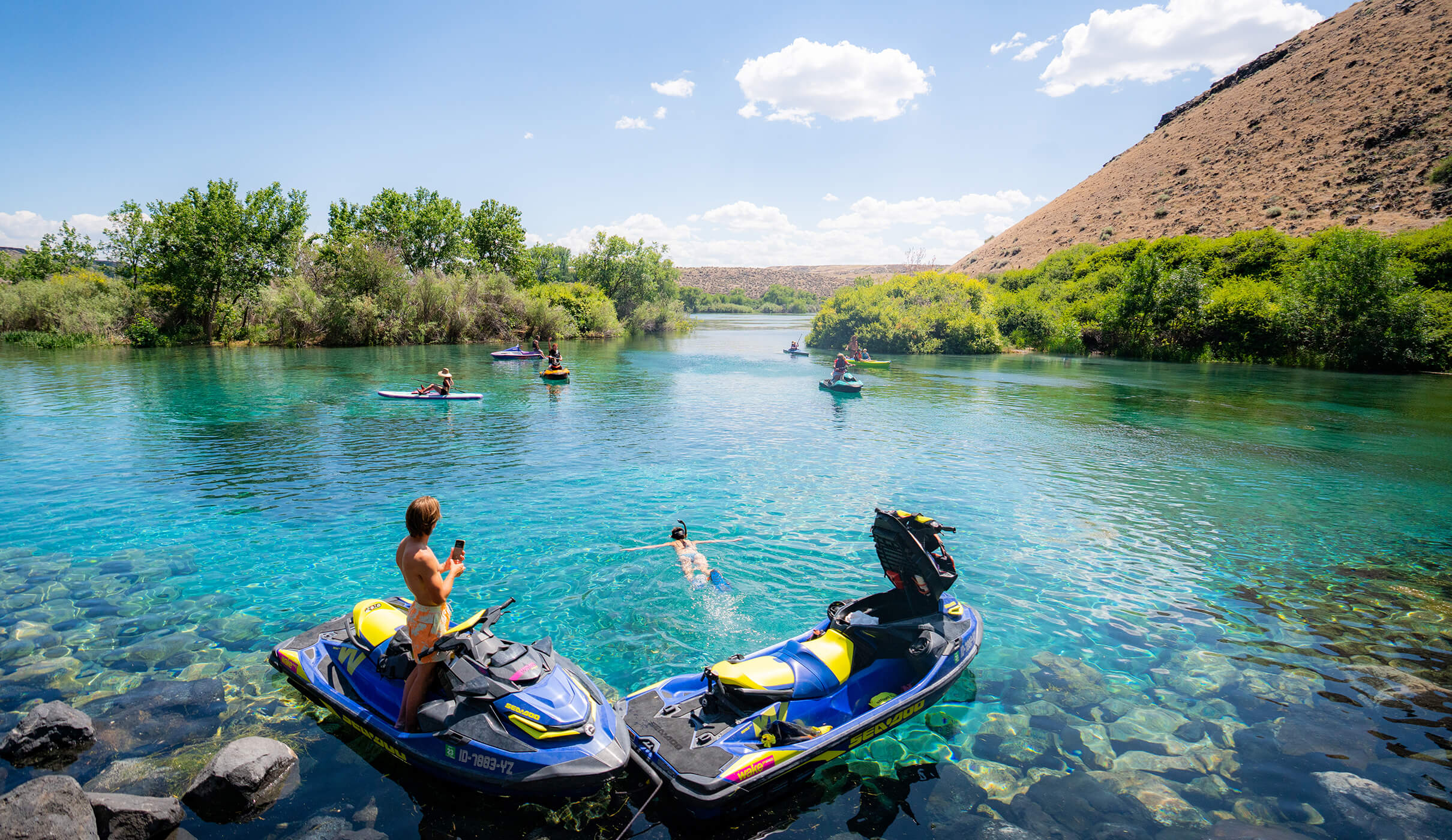 People on jet skis and paddle boards enjoy the scenic blue water at Blue Heart Springs.