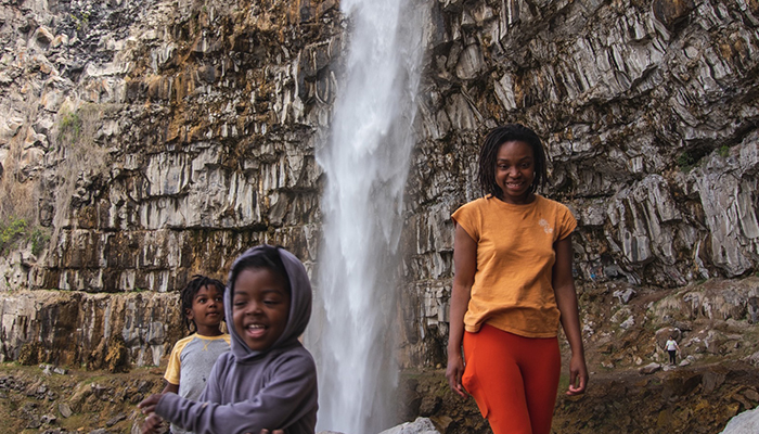 A woman and two children smile as they stand in from of the Perrine Coulee Falls.