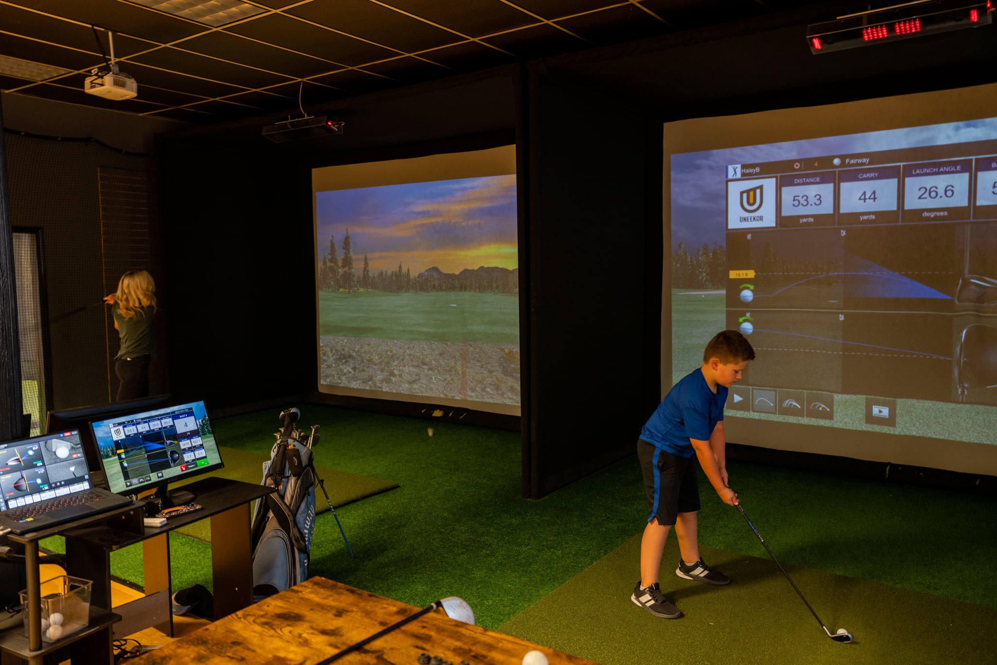 A child playing in one of two golf simulators in front of the projector.