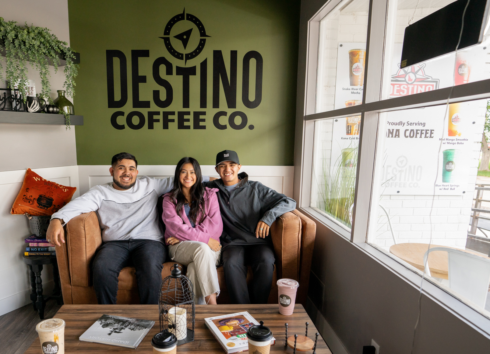The three siblings that run Destino Coffee Co sitting on a couch together at the store front.