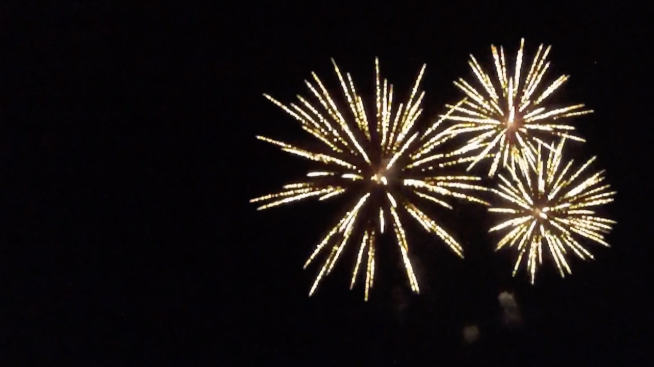 A group of three gold fireworks exploding.