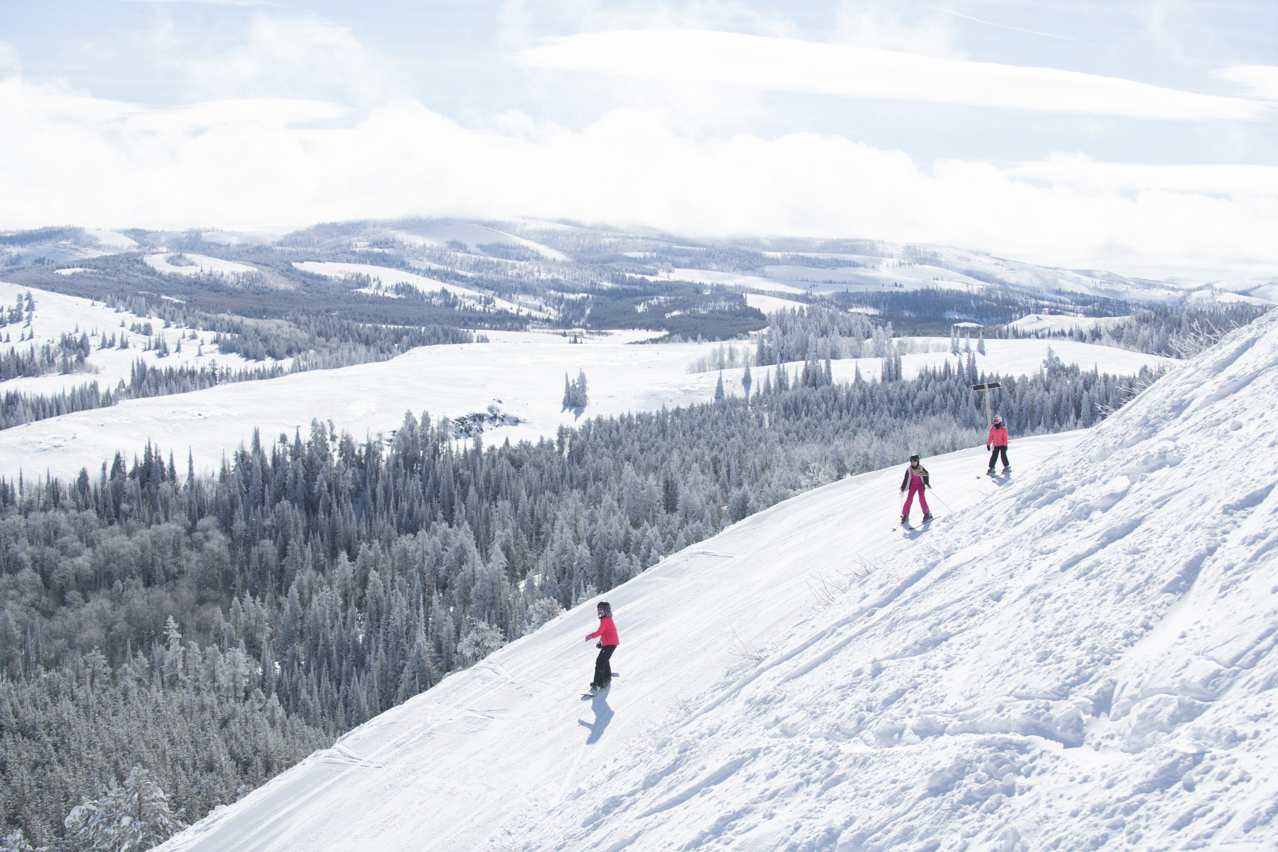 Three people skiing on the top of a snowy mountain