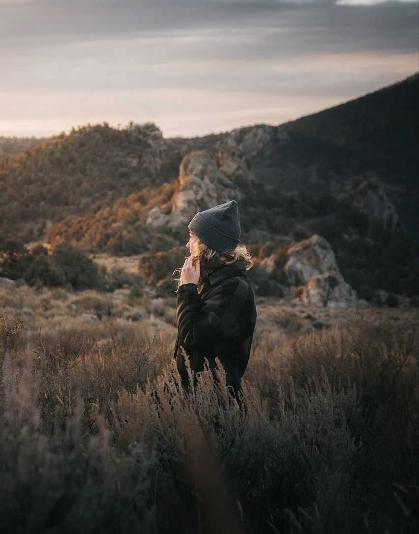 A woman in a hat standing in tall grass.