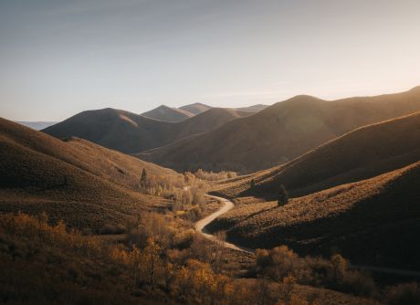 Path winding through rugged Idaho mountains at golden hour.