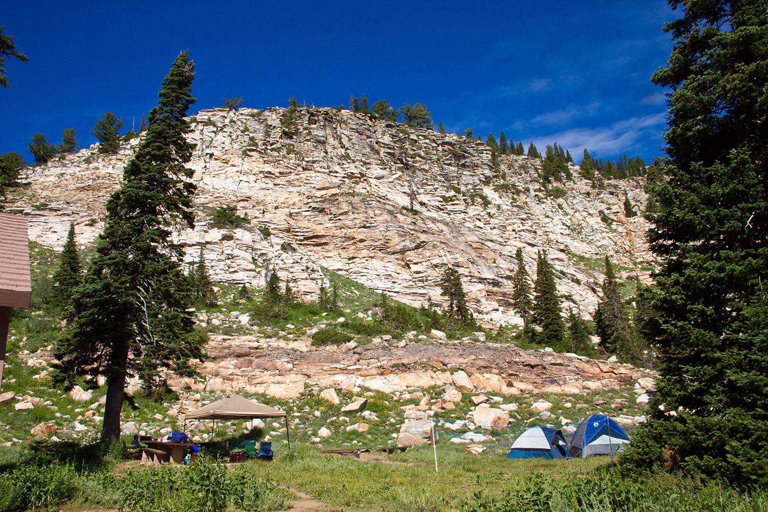 Campers enjoying a mountain campsite surrounded by pine trees and rocky cliffs in Southern Idaho.